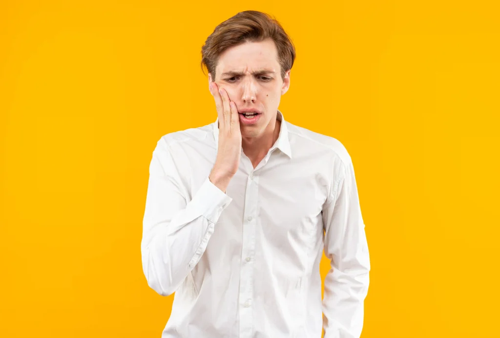 Man holding cheek due to teeth sore after cleaning discomfort
