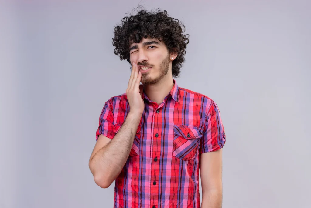 Patient touching cheek due to teeth sore after cleaning sensitivity.