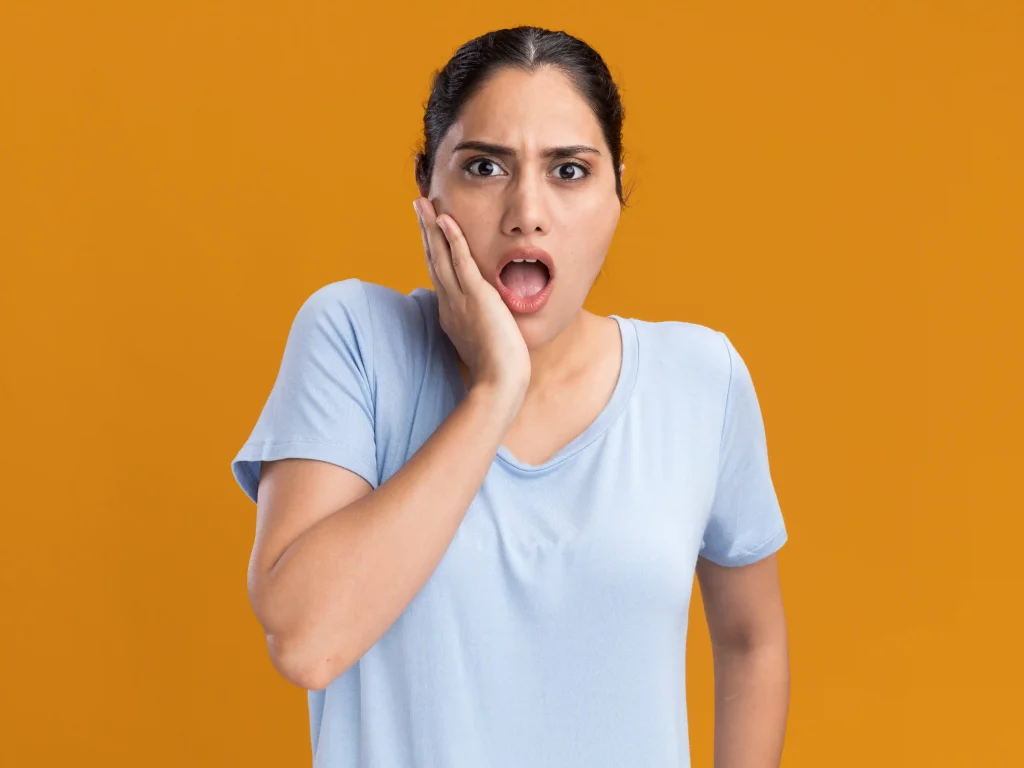 Female patient holding her face due to sore teeth after dental cleaning