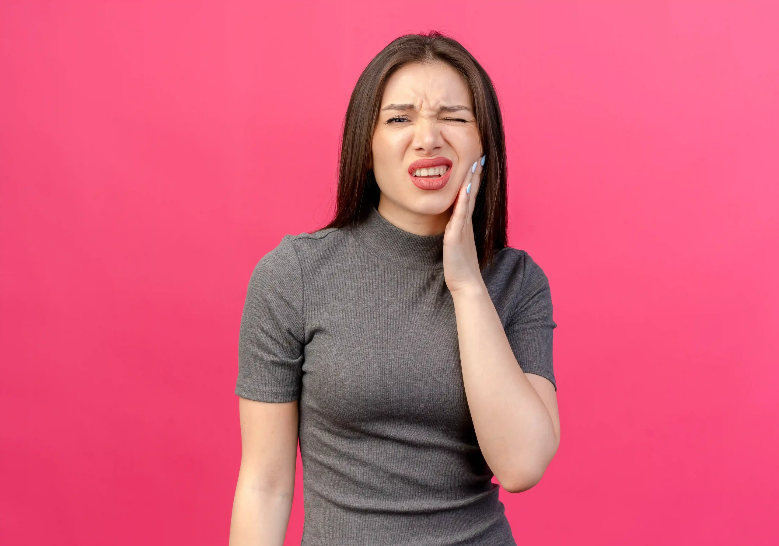 Woman holding her cheek in pain showing how teeth hurt after cleaning