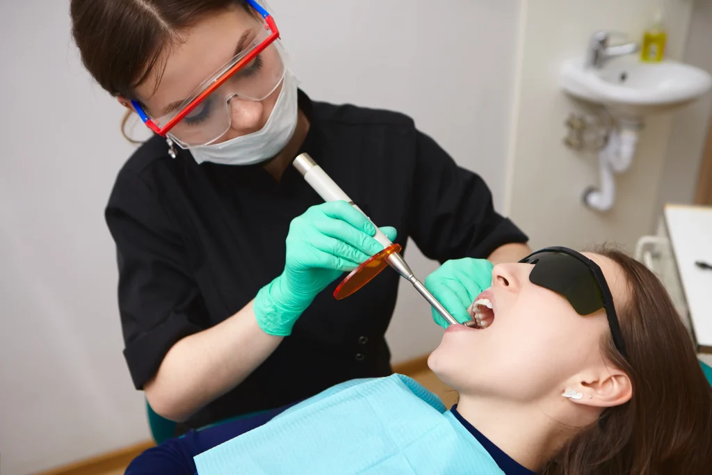 Dentist performing deep cleaning teeth for a patient wearing protective eyewear.